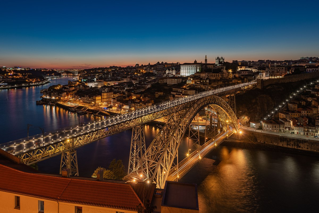 Aerial view of Porto at night, showcasing the city's glowing lights and illuminated landmarks along the Douro River.