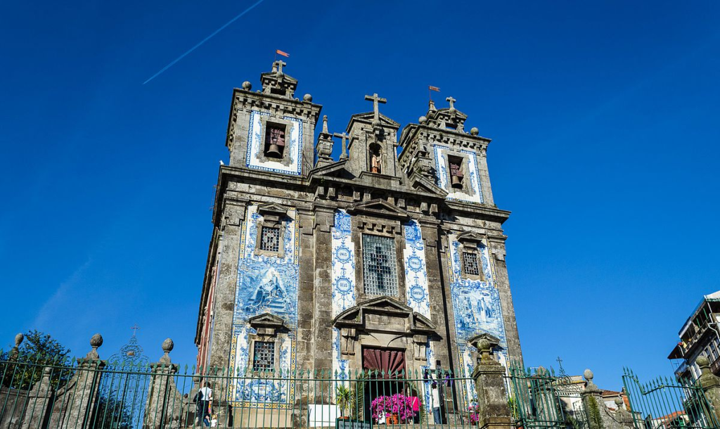 The façade of Igreja de Santo Ildefonso in Porto, adorned with traditional blue and white azulejo tiles depicting religious scenes.