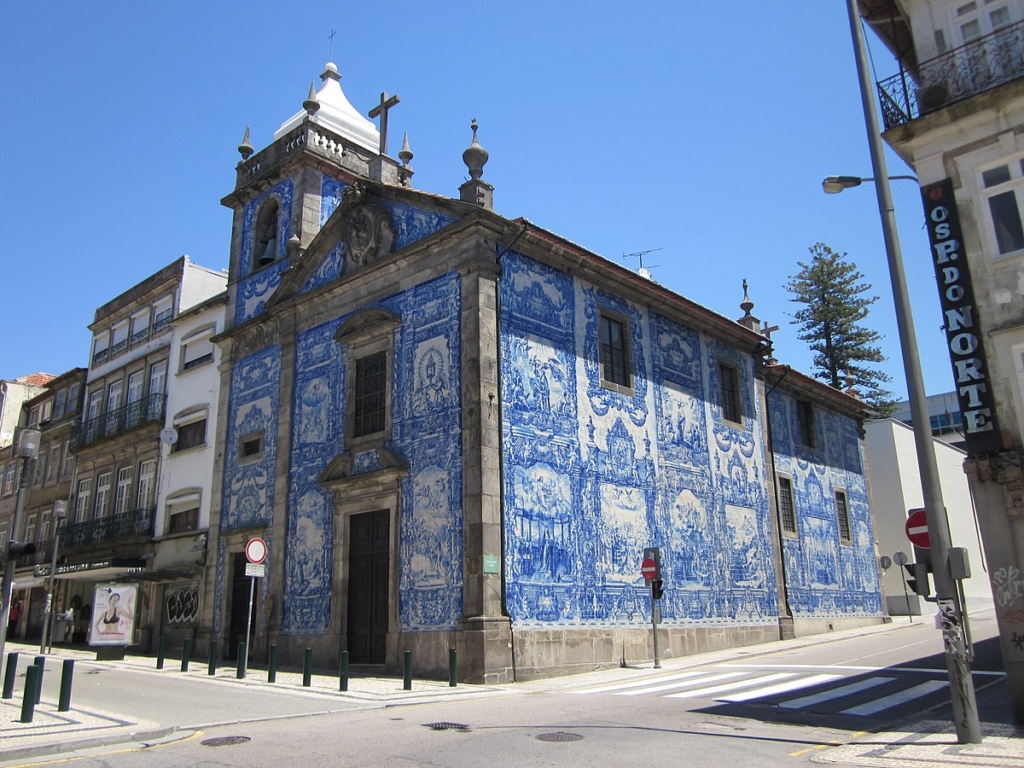 Stunning blue and white azulejo tiles cover the facade of Capela das Almas in Porto, showcasing intricate religious scenes.